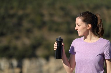 Güzel koşucu elinde su şişesiyle dağdaki manzarayı seyrediyor.