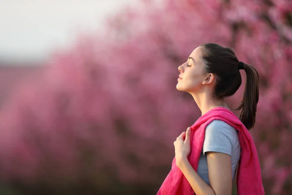 ピンクの花畑でスポーツ後に新鮮な空気を呼吸するスポーツ女性のプロフィール — ストック写真