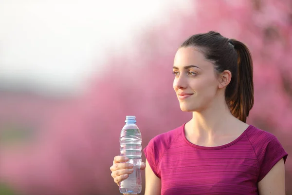 Satisfied Runner Looking Away Holding Water Bottle Exercise Pink Field — Stock Photo, Image
