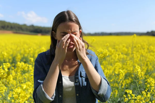 黄色の花畑で春の季節にかゆみの目を掻くアレルギーの女性 — ストック写真