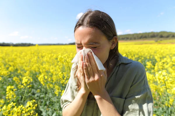 春に黄色の花畑でアレルギー咳をする女性 — ストック写真