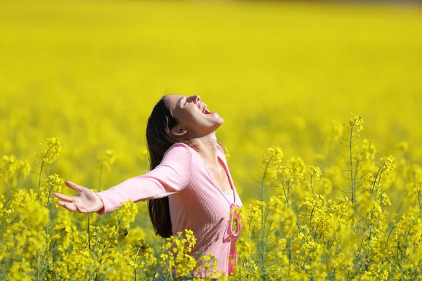 一个兴奋的女人在一片黄色的花地里尖叫着张开双臂 — 图库照片