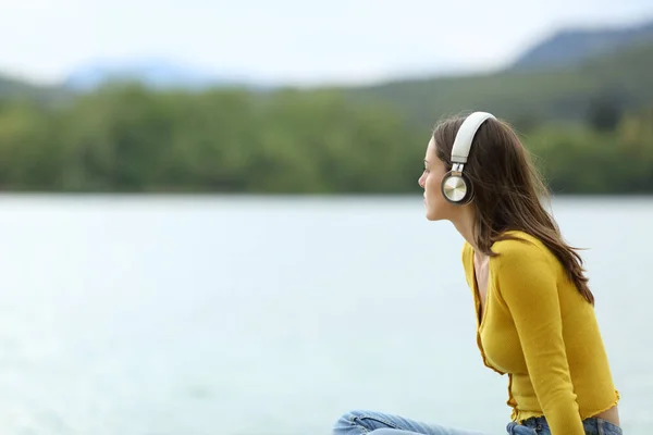 Kablosuz Kulaklıklarla Müzik Dinleyen Rahat Bir Kadın Gölde Manzara Seyrediyor — Stok fotoğraf