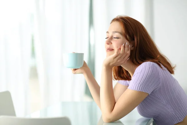 Šťastná Žena Drží Šálek Kávy Zavřenýma Očima Odpočívá Apartmánu Interiér — Stock fotografie