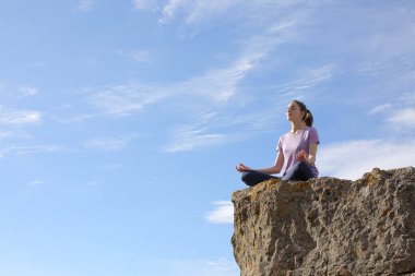 Yogi practicing yoga lotus pose in the top of a cliff