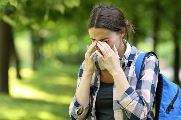 Student suffering allergy symptoms scratching itchy eyes in a park or campus