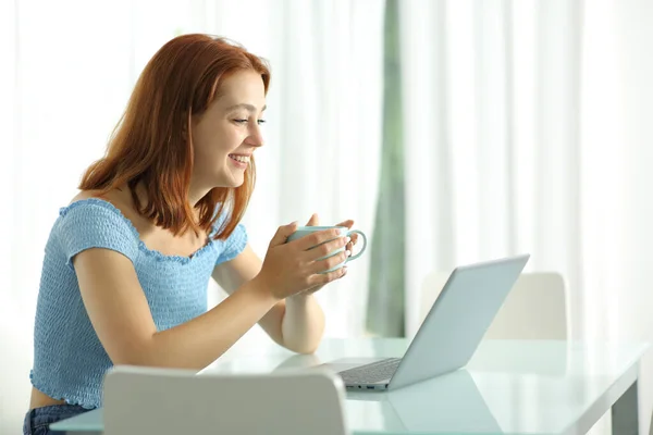 Glückliche Frau Schaut Medien Laptop Und Hält Kaffeetasse Hause — Stockfoto