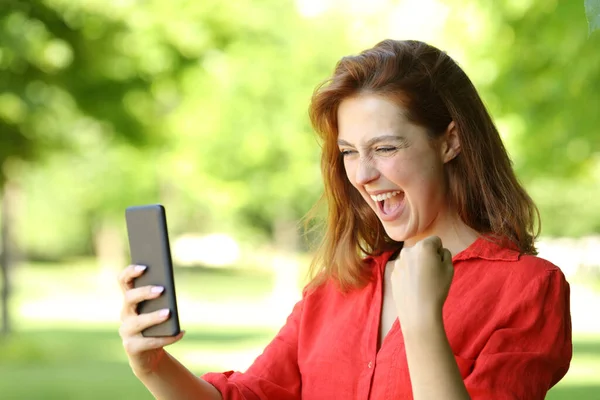 Ενθουσιασμένη Γυναίκα Κόκκινα Γιορτάζει Καλά Νέα Ελέγχοντας Έξυπνο Τηλέφωνο Ένα — Φωτογραφία Αρχείου