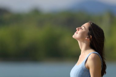 Rahatlamış bir kadının profili. Temiz hava soluyor. Gölün kenarında meditasyon yapıyor.