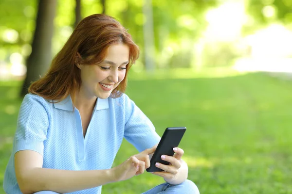 Ευτυχισμένη Γυναίκα Που Χρησιμοποιεί Ένα Κινητό Τηλέφωνο Έλεγχο Περιεχόμενο Κάθεται — Φωτογραφία Αρχείου