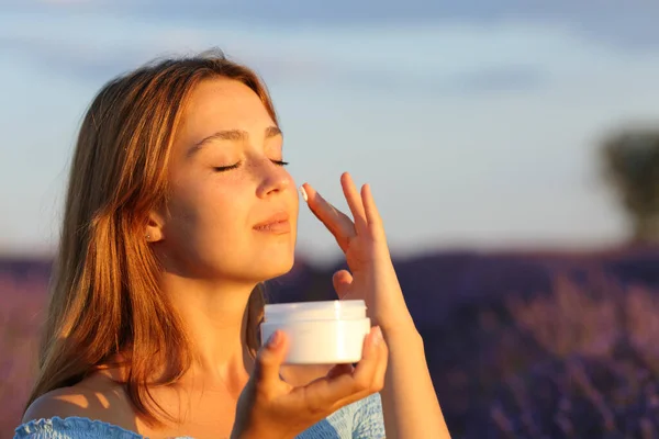 Skönhetskvinna Som Applicerar Fuktighetskräm Kinden Lavendelfältet Vid Solnedgången — Stockfoto