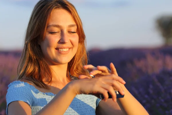 日没時にラベンダー畑で手に保湿クリームを適用する幸せな女性 — ストック写真