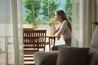 Terasta oturmuş çay içen bir kadının profili.