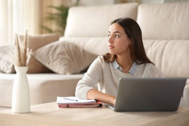 Dikkati dağılmış bir öğrenci bir evin zemininde oturuyor.