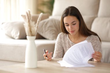 Kendine güvenen bir kadın evdeki kahve masasını imzalamadan önce form veya kontrole gider.