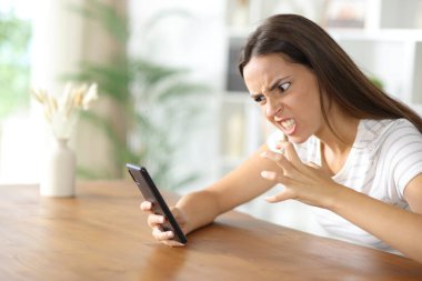 Kızgın kadın evdeki cep telefonundan sinir bozucu haberlere bakıyor.