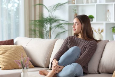 Rahat bir kadın kanepede oturup pencereden bakıyor.