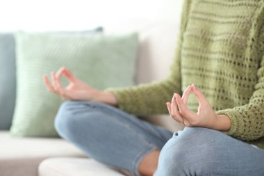 Yeşiller içinde yoga yapan sıradan bir kadının evinde kanepede oturması.