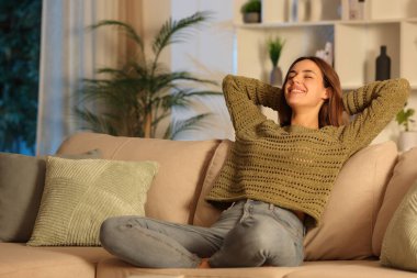 Yeşilli mutlu kadın, gece evde bir kanepede dinleniyor.