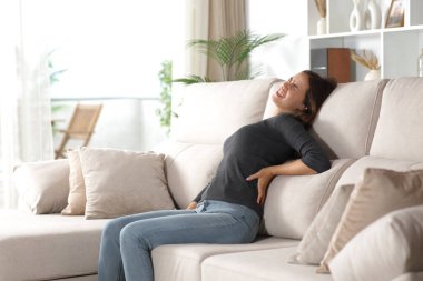 Evdeki rahat koltukta oturan bir kadın sırt ağrısından şikayetçi.