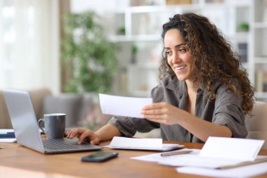 Faturaları kontrol eden ve evde çalışan bir bilgisayarla online muhasebe yapan mutlu bir serbest yazar.