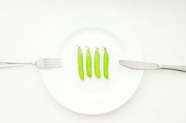 Four green peas in beans on whute plate — Stock Photo, Image
