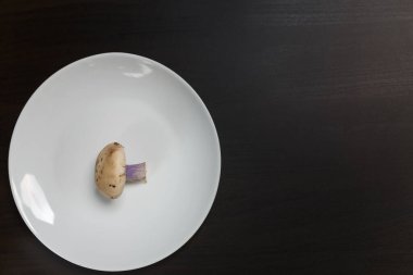 Siyah masadaki beyaz tabakta tricholoma mantarları. Diyet, beslenme, sağlıklı ve sağlıksız yeme alışkanlıkları, kilolu ya da zayıf konsept.