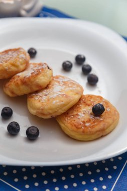 Geleneksel şurup ya da süzme peynirli krep, beyaz tabakta yaban mersini ve mutfak masasında mavi peçete.. 