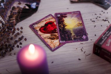 Kehanet kartları mor yanan mum ve kuru lavanta ile aynı hizada. Gizem, astroloji, okültizm, falcılık ve inanç kavramı.