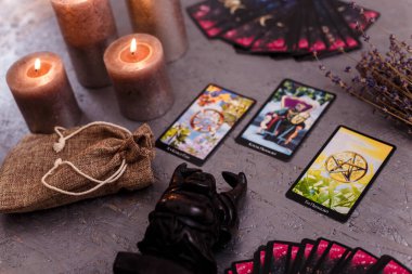Kehanet kartları siyah Buda heykeli, para banknotları ve mumlarla aynı hizada. Gizem, astroloji, falcılık, inanç, refah ve zenginlik kavramı.