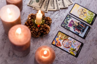 Kehanet kartları para ve yeşil mumlarla aynı hizada. Gizem, astroloji, falcılık, inanç ve zenginlik kavramı. 