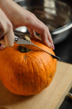 Kesme tahtasında balkabağı doğrayan bıçaklı kadın eller. Sonbahar sebzeleri hazırlanıyor. Sağlıklı organik vejetaryen gıda konsepti. 