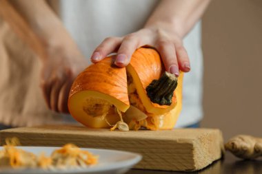 Kesme tahtasında balkabağı doğrayan bıçaklı kadın eller. Sonbahar sebzeleri hazırlanıyor. Sağlıklı organik vejetaryen gıda konsepti. 