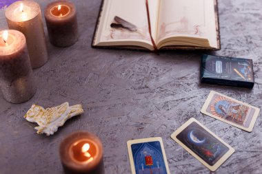 Kehanet kartları tüylerle aynı hizada ve gümüş arka planda mumlar. Gizem, astroloji, falcılık, inanç, bilgelik ve bilgi kavramı. 