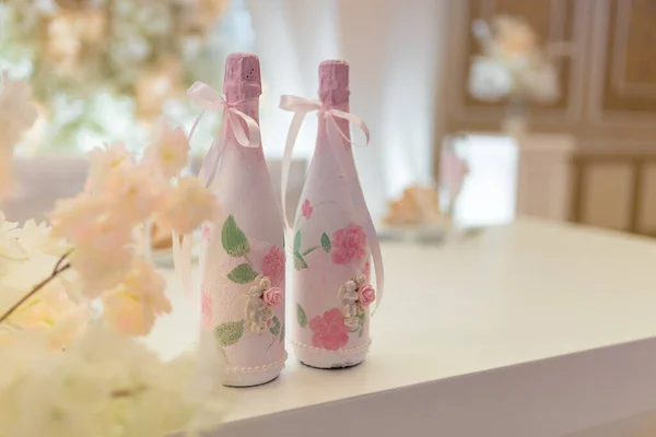 两个婚礼香槟酒瓶装饰花边 花和丘比特天使站在节日桌上 软集中拍摄 复制空间 — 图库照片