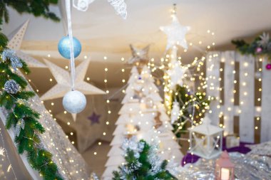 Odaklanmamış arka planda parlak parlak çelenk ışıkları ve bokeh ile asılı gümüş ve mavi takılar. Noel ağacı oyuncakları ve yeni yıl süslemeleri. Kış tatili mucizesi.