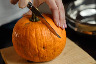 Kesme tahtasında balkabağı doğrayan bıçaklı kadın eller. Sonbahar sebzeleri hazırlanıyor. Sağlıklı organik vejetaryen gıda konsepti. 