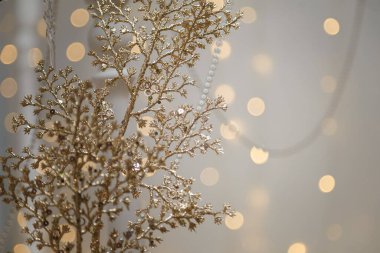 Yılbaşı ışıklarının arka planındaki altın parlak dalın yumuşak odaklı görüntüsü. Neşeli atmosfer, tatil ruhu, yeni yıl kutlaması konsepti. Boşluğu kopyala