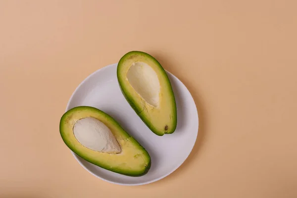 Twee Helften Groene Verse Avocado Met Zaad Witte Plaat Beige — Stockfoto