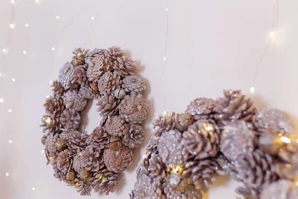 Twee Kerstkransen Gemaakt Van Dennenappels Met Glanzende Bloemenslinger Lichten Opknoping — Stockfoto