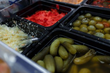 Market, süpermarket, alışveriş merkezi, hipermarket veya alışveriş merkezindeki sebze bölümünün hafif odaklı görüntüsü. Turşulu yeşil ve kırmızı domatesler, lahana, zencefil ve salatalık.. 