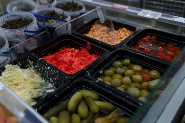Market, süpermarket, alışveriş merkezi, hipermarket veya alışveriş merkezindeki sebze bölümünün hafif odaklı görüntüsü. Salamura yeşil ve kırmızı domatesli kutular, lahana, zencefil, karides ve salatalık. 