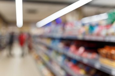 Süpermarketin iç mekanının odaklanmamış görüntüsü. Bulanık hipermarket, alışveriş merkezi ya da alışveriş merkezi geçmişi. Tanınmayan insanlarla dolu sıra sıra marketler ve raflar..