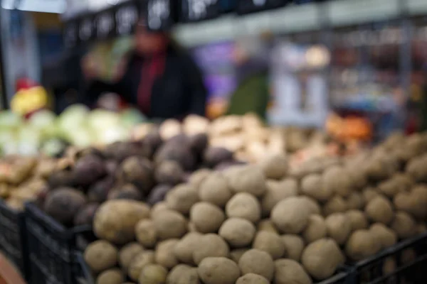 Soft focused shot of vegetable department in grocery store, supermarket, mall, hypermarket or shopping center. Boxes with beetroot and potatoes, unrecognizable people on background. Healthy organic food concept.