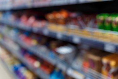 Süpermarketin iç mekanının odaklanmamış görüntüsü. Bulanık hipermarket, alışveriş merkezi ya da alışveriş merkezi geçmişi. Market departmanının sıraları ve rafları.