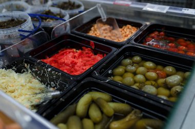 Market, süpermarket, alışveriş merkezi, hipermarket veya alışveriş merkezindeki sebze bölümünün hafif odaklı görüntüsü. Salamura yeşil ve kırmızı domatesli kutular, lahana, zencefil, karides ve salatalık. 