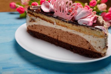 Pastanın yarısı beyaz tabakta, mavi tabakta. Yapay bahar çiçekleri olan tatlı bir fırın