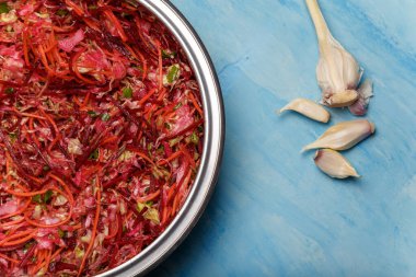 Fırça adında metal bir kase salata. Pancar, havuç ve lahanayla ince şeritler halinde kesilmiş sarımsak ve ahşap kaplama. Vejetaryen, organik, sağlıklı yiyecekler, diyet, beslenme. Üst görünüm, alanı kopyala.