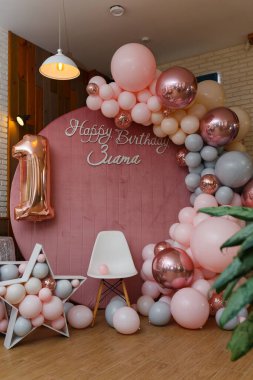 Güzel şenlik süslemeleri, pembe ve gri balonlar kemer, tahta yıldızlar, beyaz sandalye ve ahşap arka planda bir numaralı balon. 1 yaşında küçük bir kızın doğum günü partisi fotoğrafı..