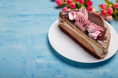 Pastanın yarısı beyaz tabakta, mavi tabakta. Yapay bahar çiçekleri olan tatlı bir fırın